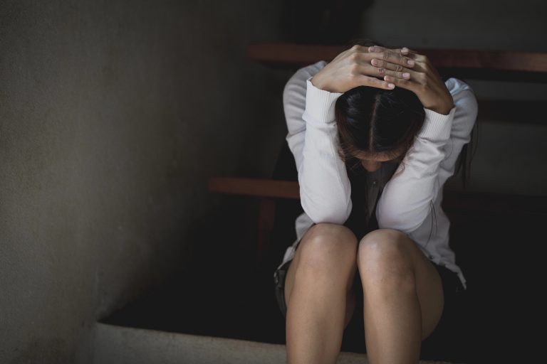 Menina sentada com a mão na cabeça